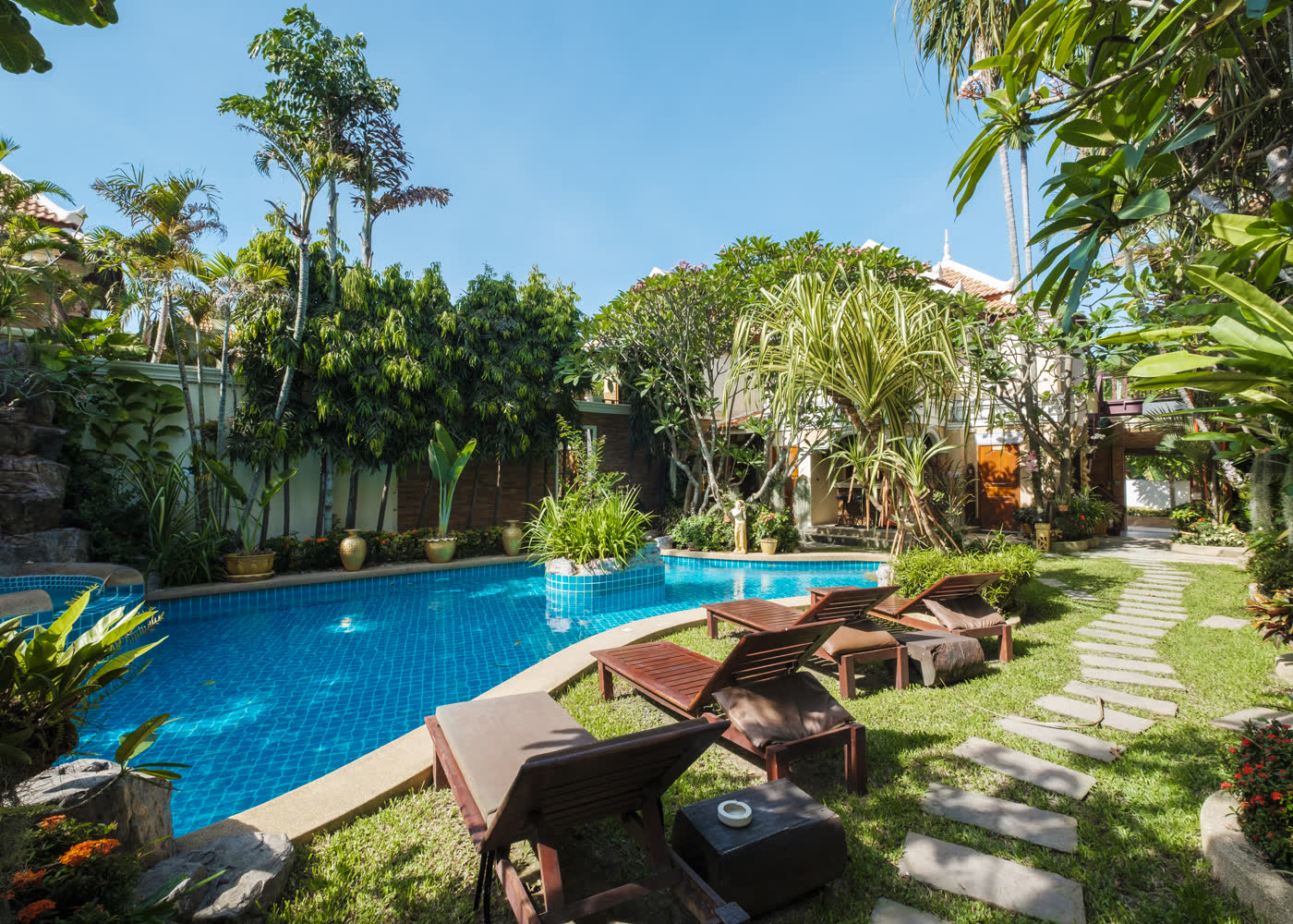 Piscina com espreguiçadeiras e jardim tropical